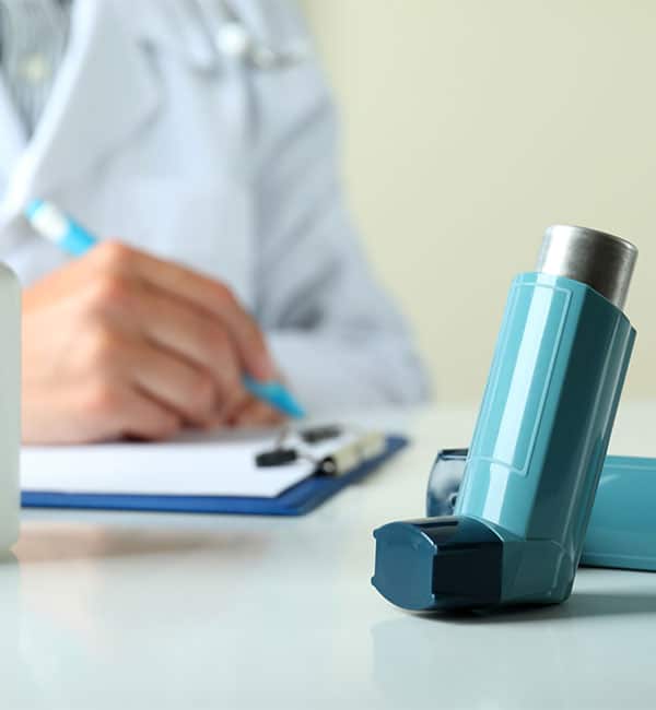 doctor writing something while showing inhaler
