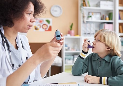 Doctor teaching a young boy how to use an asthma inhaler.