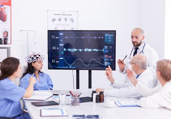 Doctors discussing brainwave data with a patient wearing an EEG cap.
