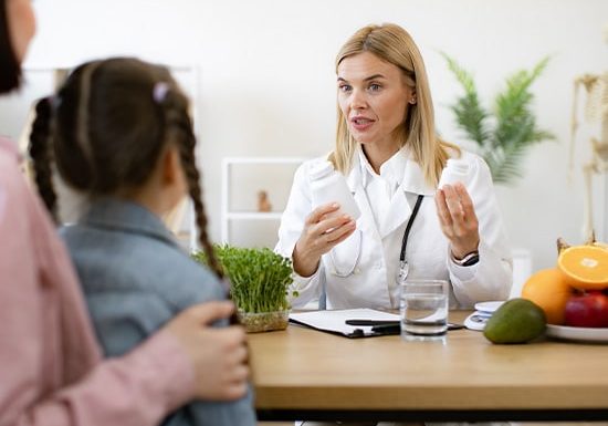 Doctor explaining medication to a mother and daughter during a consultation.