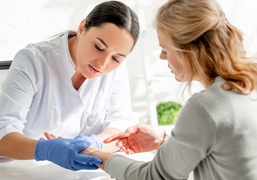Female doctor examining a patient’s hand in a bright clinic.